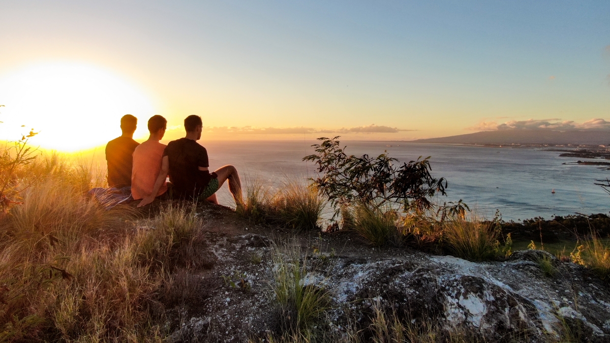 Travellers watching the sunset over the coast